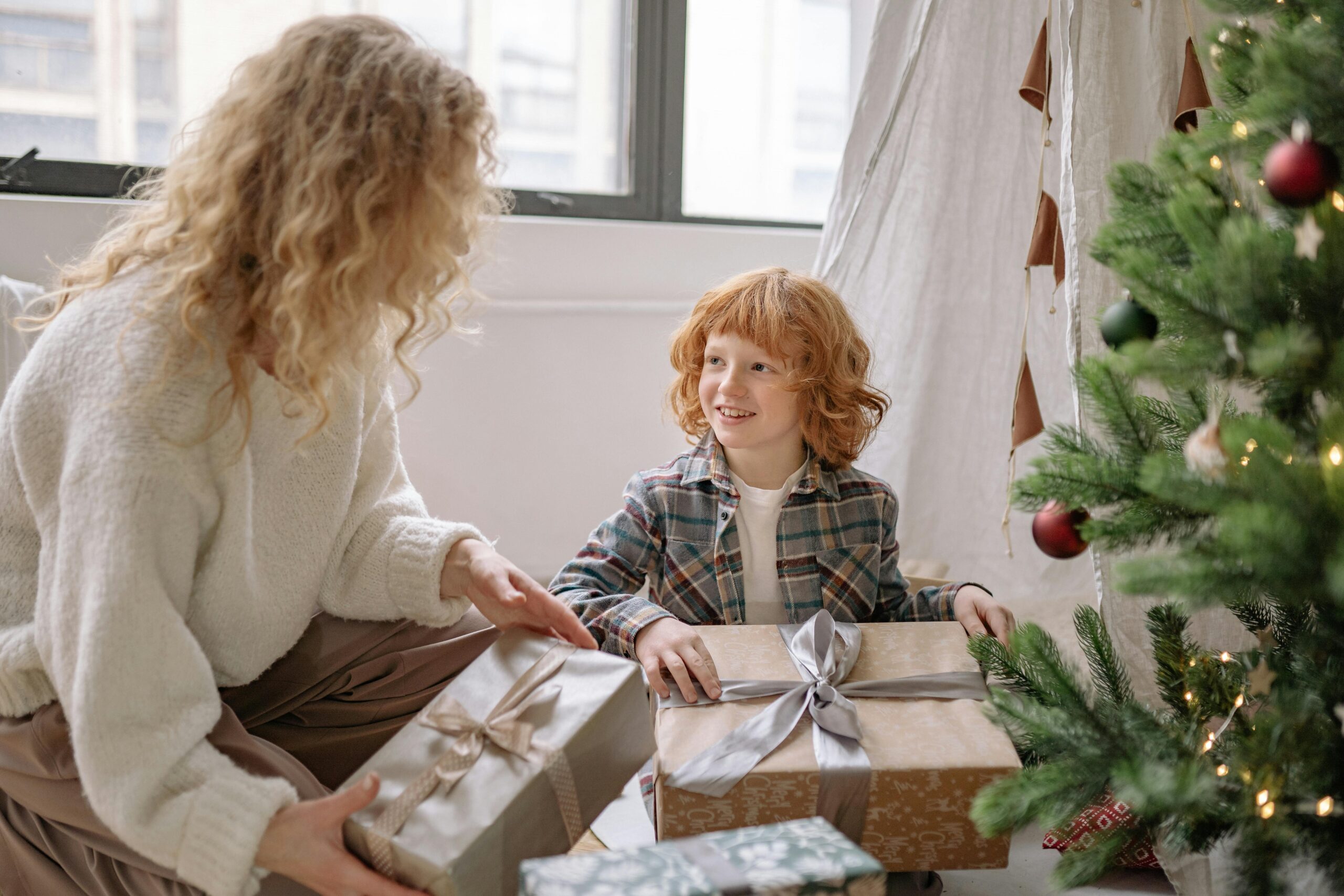 A joyous moment between mother and son unwrapping Christmas gifts by the decorated tree indoors.find the perfect gift for every occasion