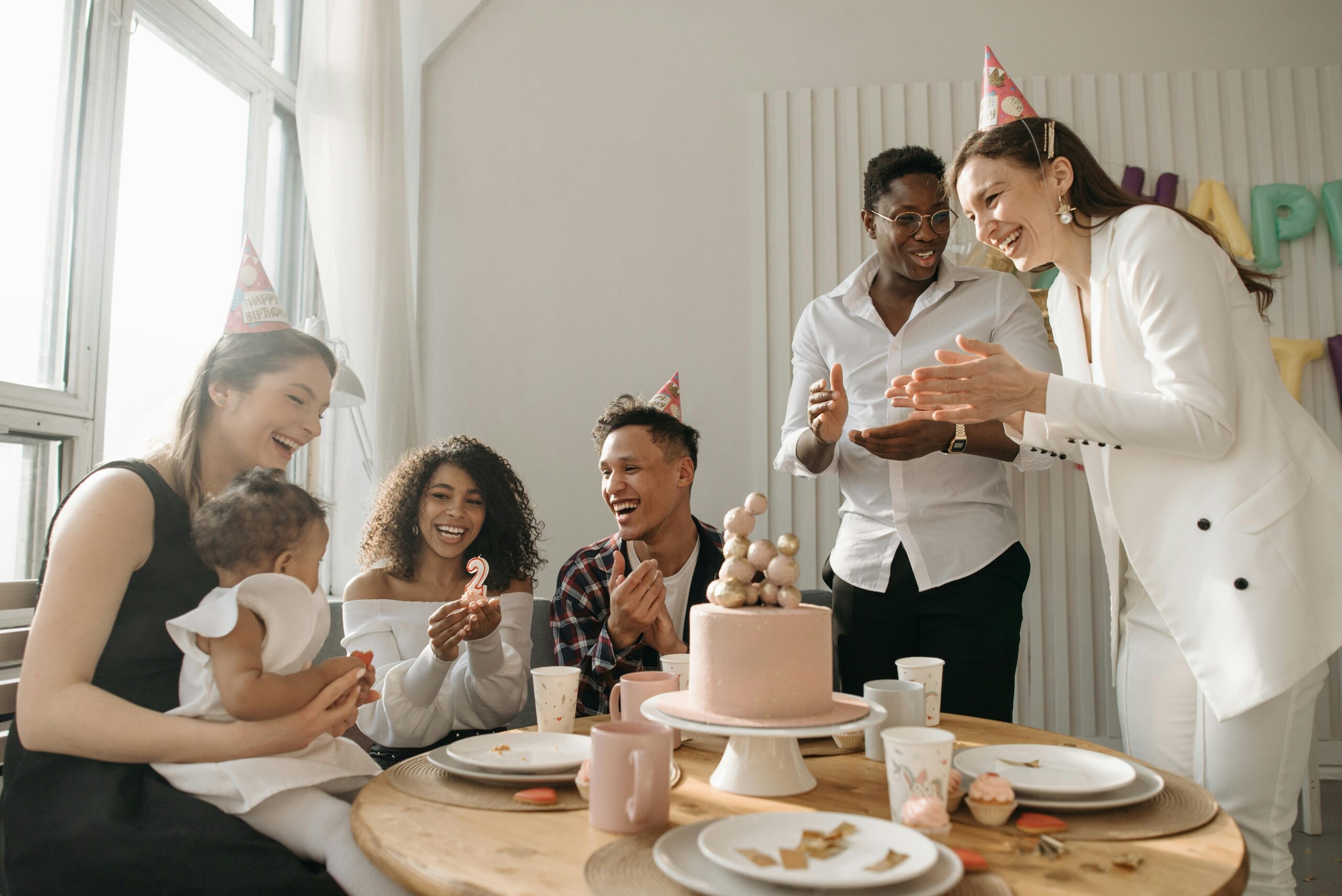 A diverse group of friends celebrating a birthday at home with cake and laughter.